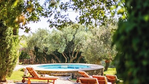A swimming pool with lounge chairs, surrounded by trees and a stone wall. - Garden Oasis Pool Villa (Konavle)