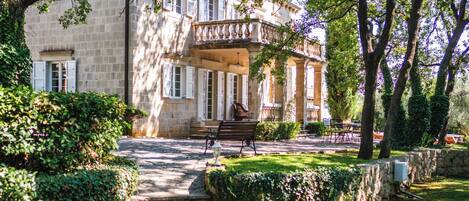 A stone pathway leading to a building with a balcony.