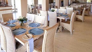 Un vaste espace dédié à la salle à manger, doté de nombreuses tables et chaises, avec une palette de couleurs neutres et un design architectural moderne.