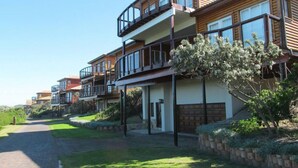 Une rangée d’immeubles résidentiels modernes à plusieurs étages, dotés de balcons, d’une allée pavée et d’un aménagement paysager bien entretenu.