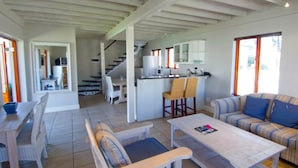 Un grand espace de vie comprenant un canapé, une table basse et une table à manger. Il y a également un coin cuisine avec un réfrigérateur et un évier.