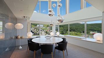 A modern dining area with a round table, black chairs, and hanging spherical light fixtures.