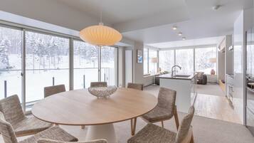 A modern dining area with a round table, wicker chairs, and a hanging light fixture.