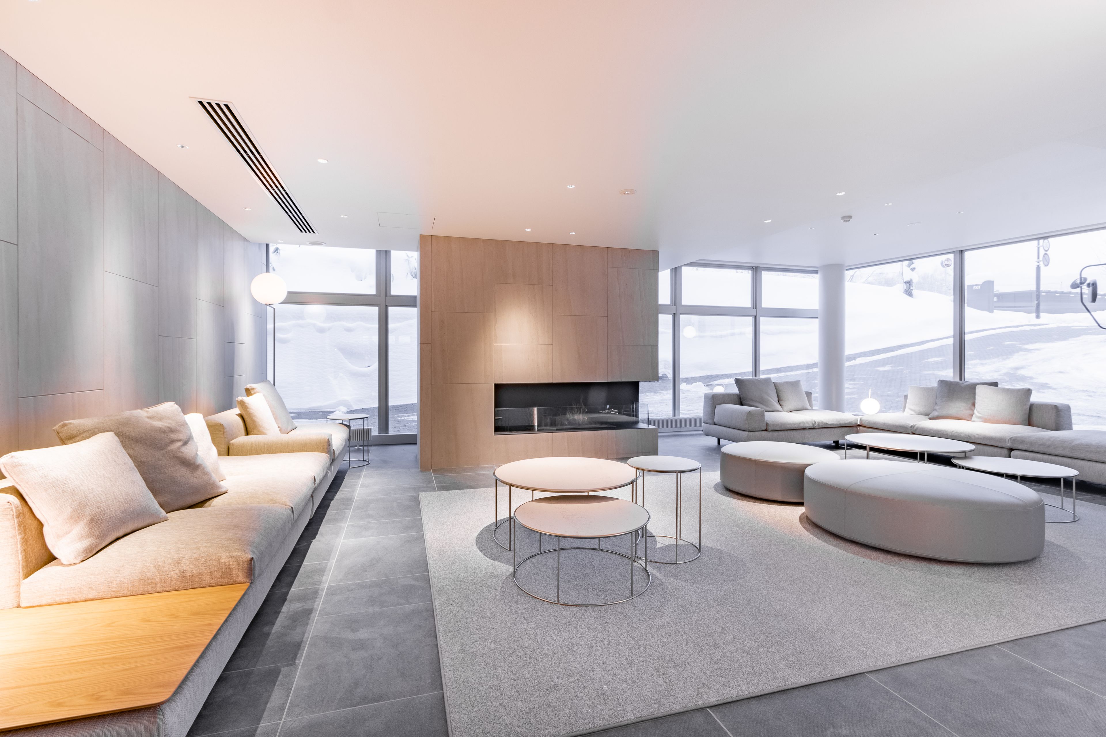 A modern living room with a fireplace, sofas, and round tables.