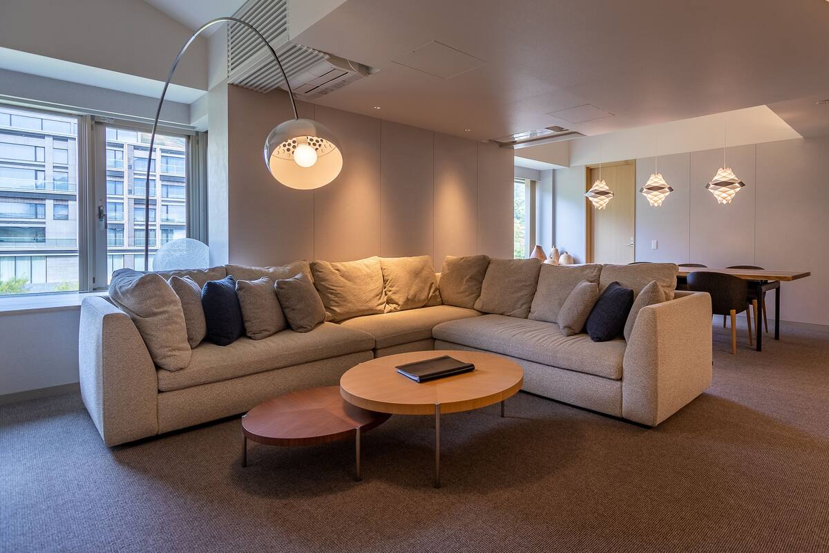 A modern living room with a sectional sofa, a round coffee table, and pendant lighting.