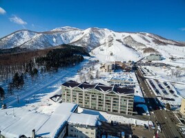 Une ville de montagne enneigée, avec un grand hôtel comprenant de nombreux étages et un parking.