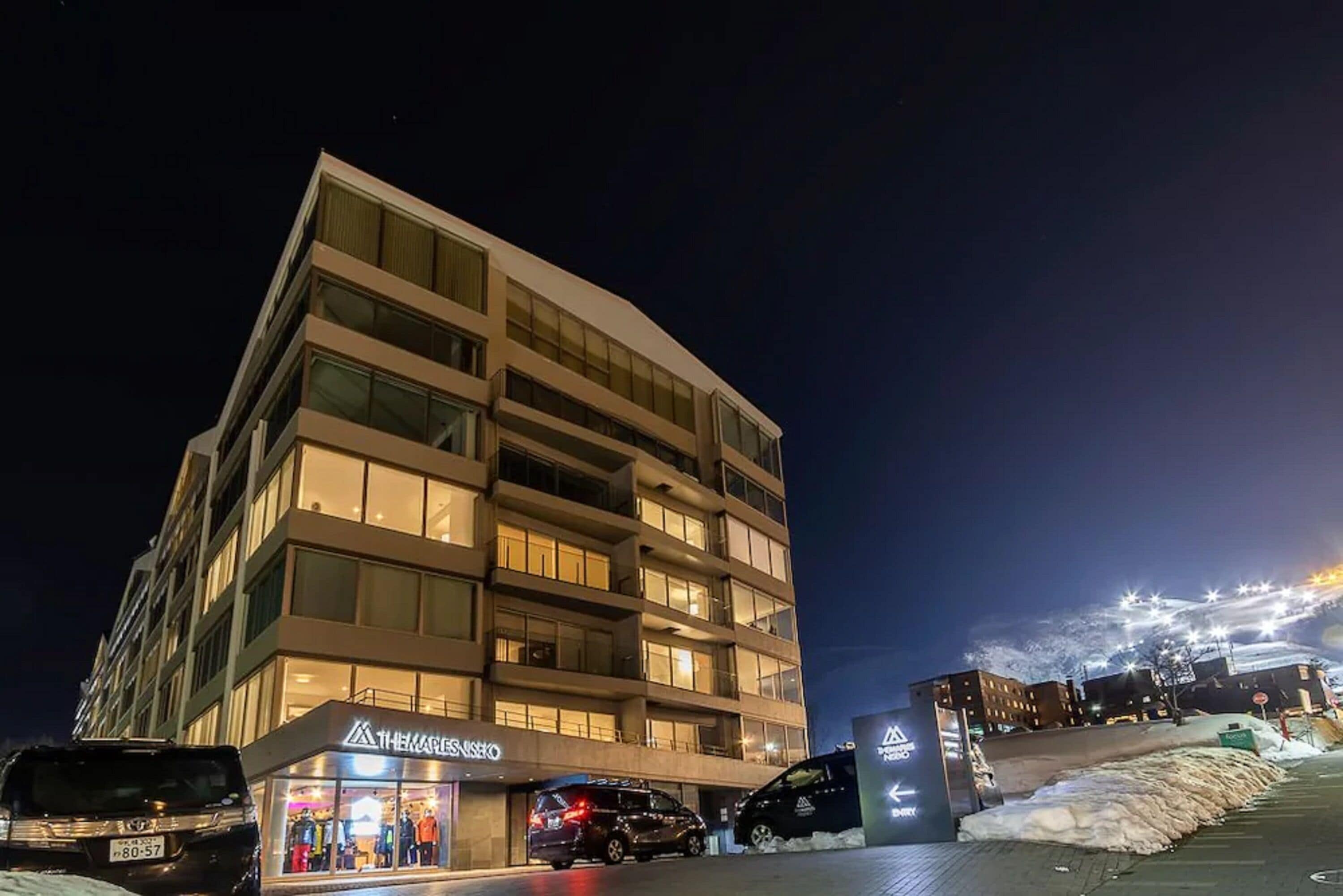 A multi-story hotel with a modern design, featuring a ground-level retail space and a parking area.
