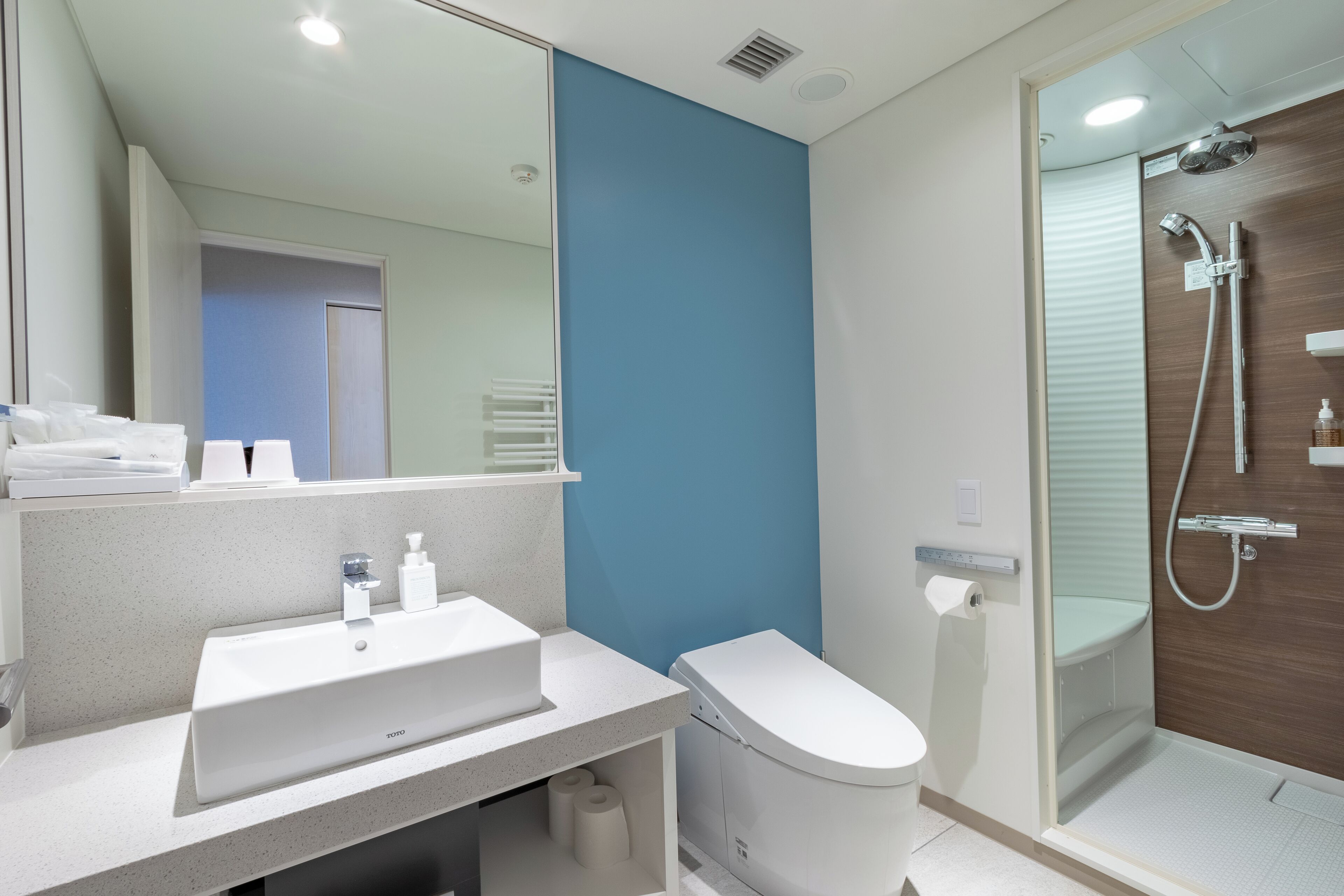 Une salle de bain moderne avec un lavabo, des toilettes et une douche, le tout de couleur blanche.