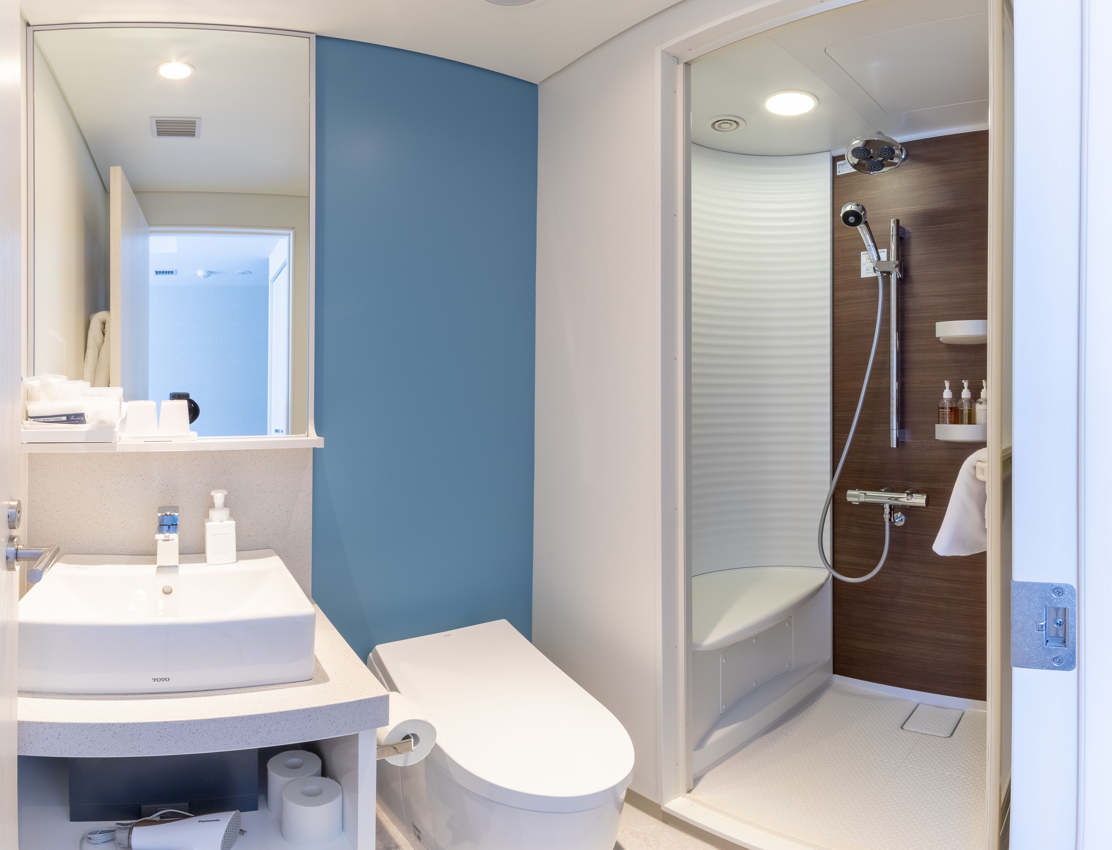 Un baño moderno con lavamanos, inodoro y ducha blancos.