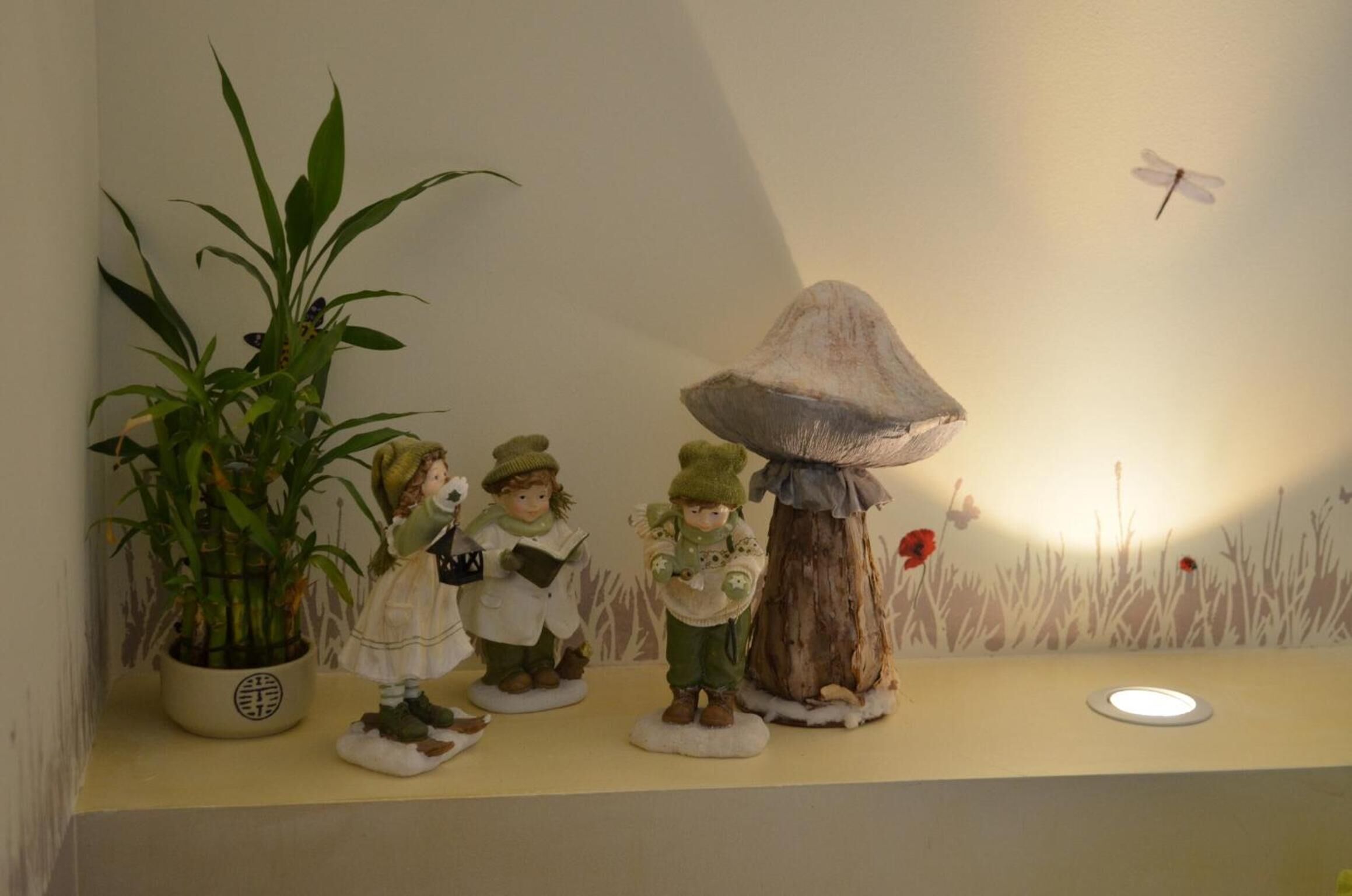 A shelf with figurines, a potted plant, and a wall mural.