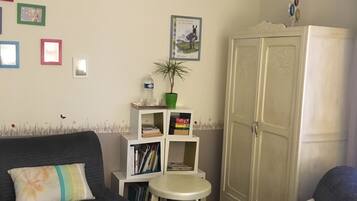 Una sala de estar con dos sofás oscuros, una mesita redonda, una estantería y un aparador.