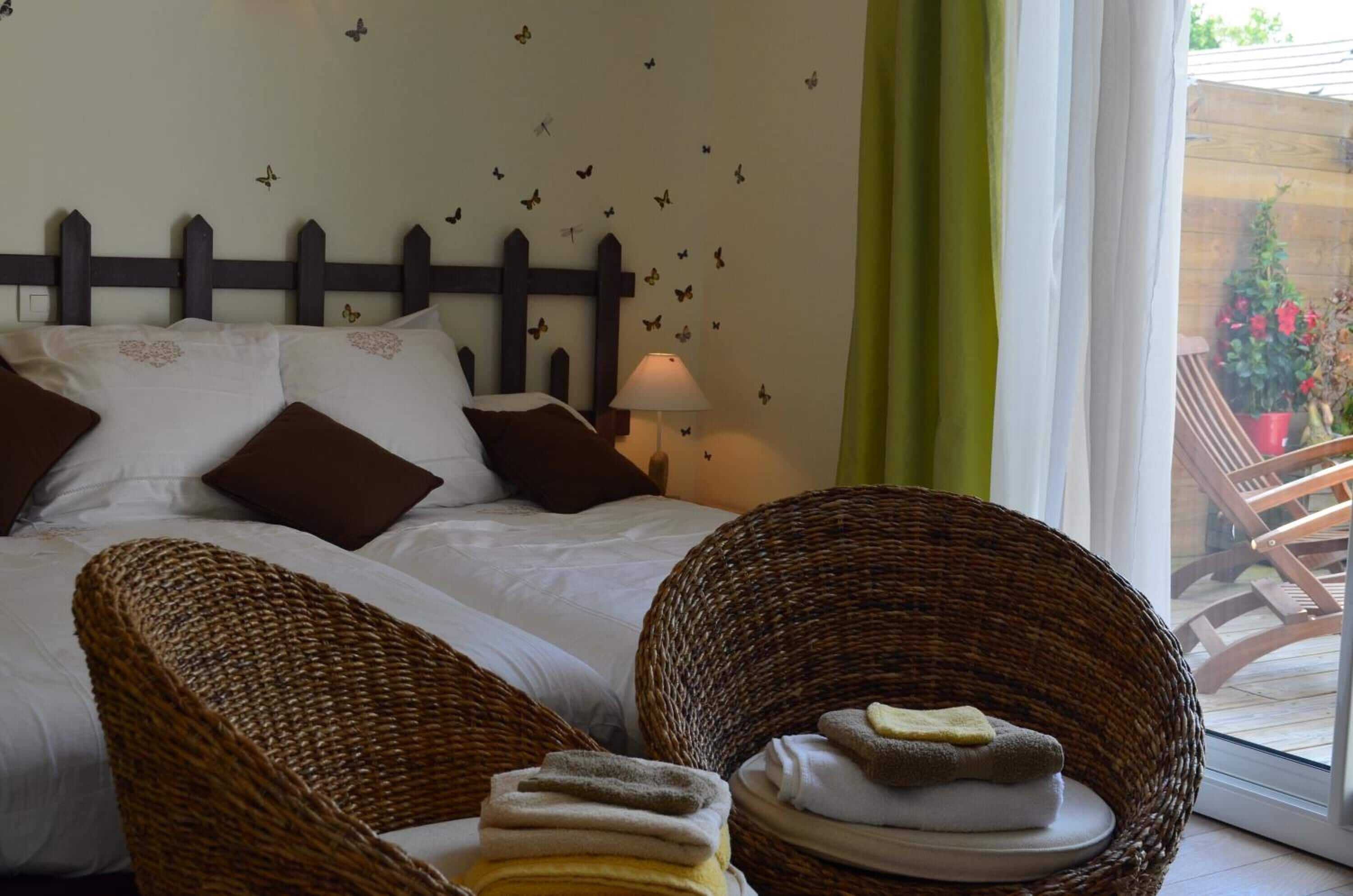 Een slaapkamer met een bed, kussens, een lamp en rieten meubels.