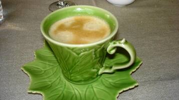 Una taza de café sobre un platito verde con diseño de hoja.