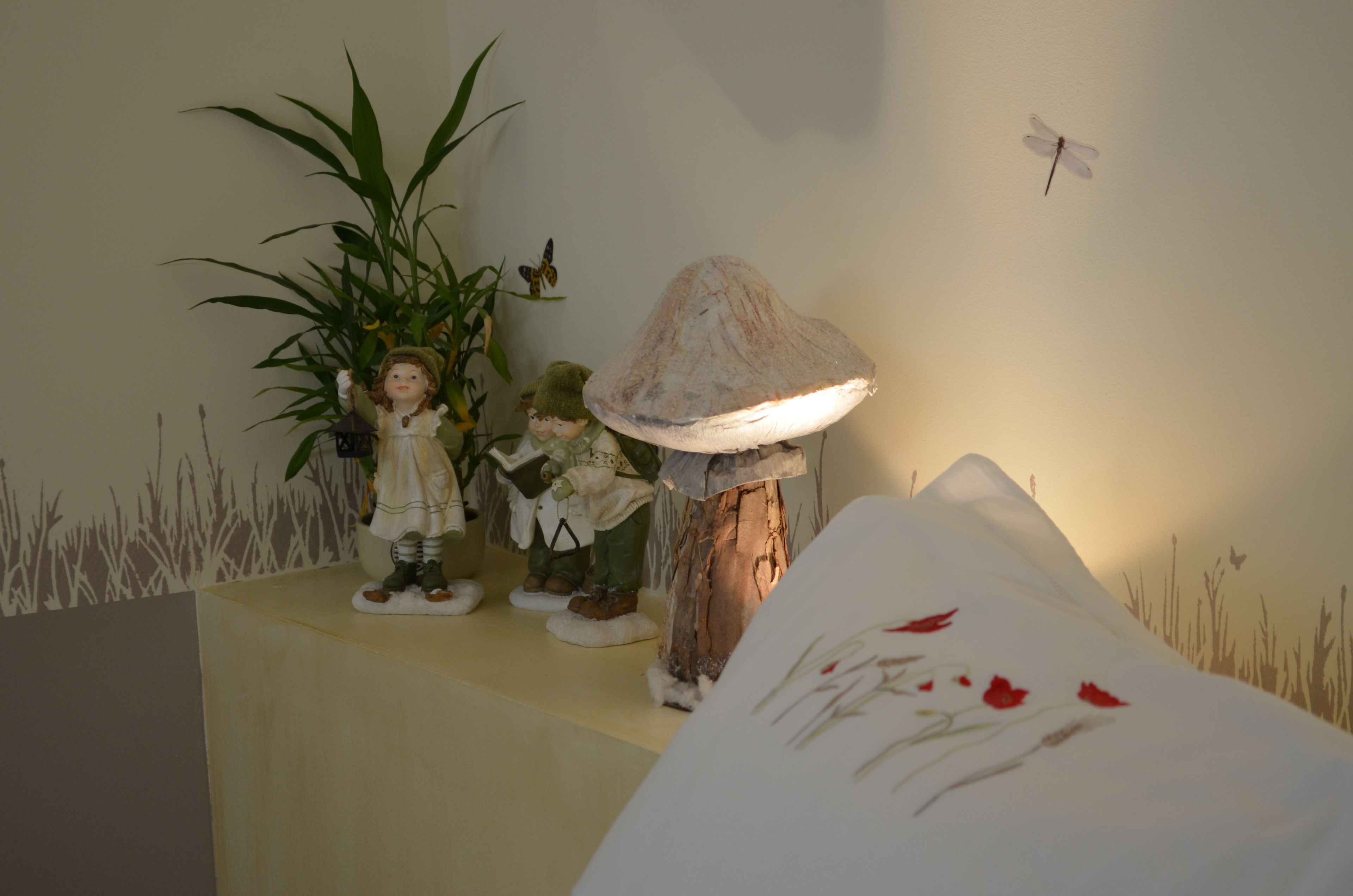 Et værelse med en seng, en lampe og pynteting.