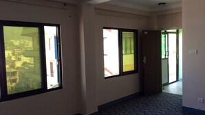 A hallway with large windows, carpeted floor, and a door leading to another room. - Asian Himalaya Home Stay (Kathmandu)
