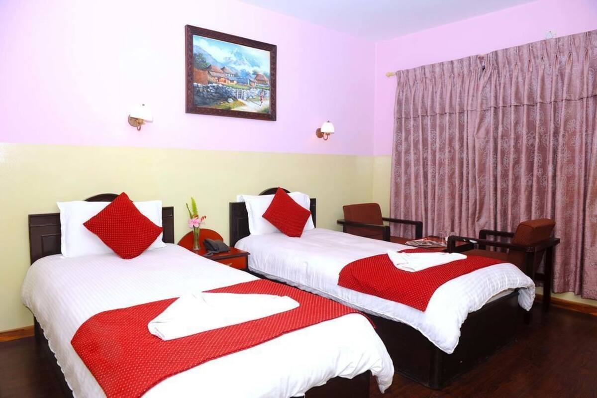 A hotel room with two beds, each with red and white bedding, a painting on the wall, and a large window with curtains.