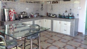 A modern kitchen with granite countertops, stainless steel appliances, and a glass dining table. - Asian Himalaya Home Stay (Kathmandu)