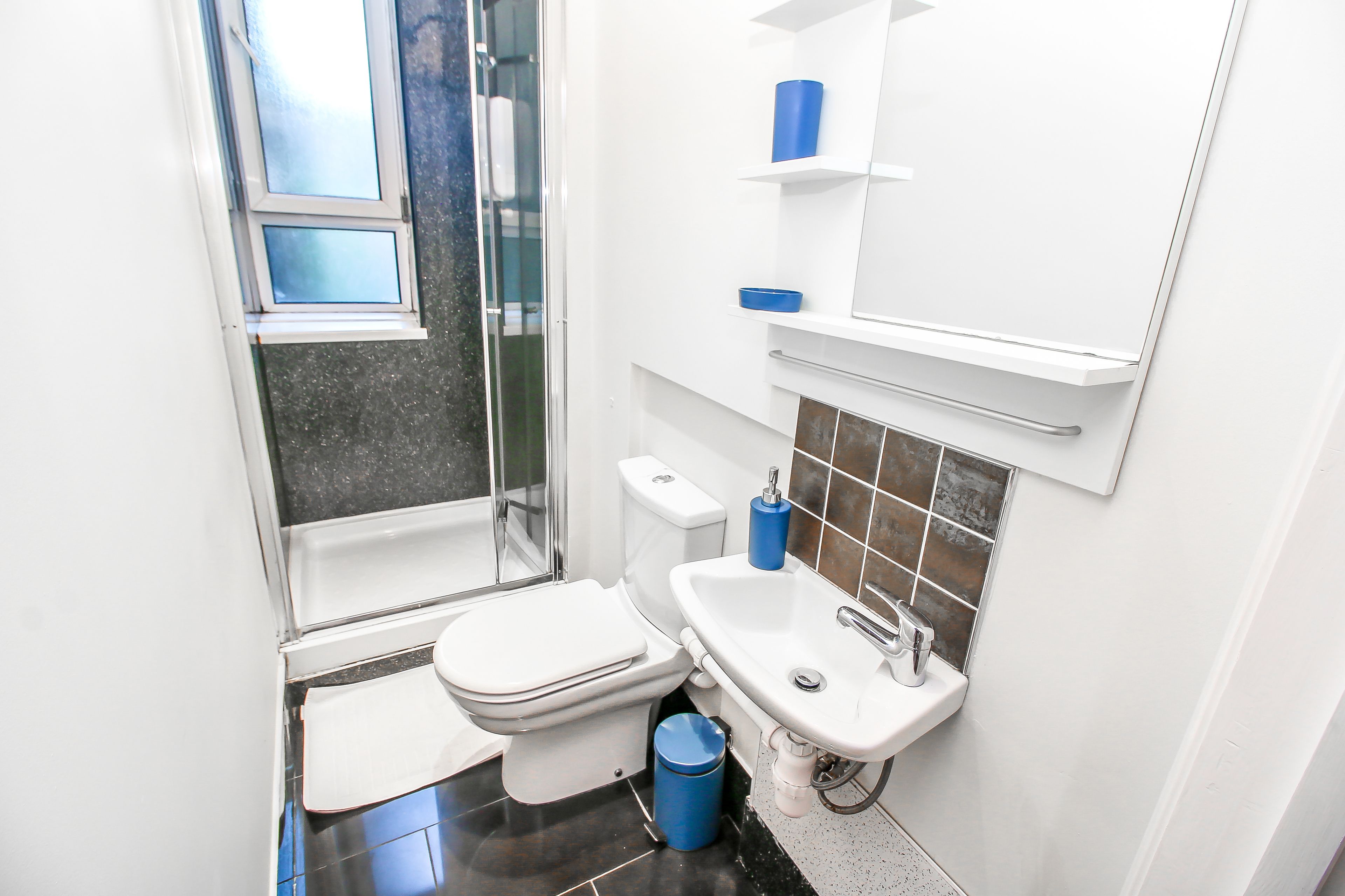 Un baño pequeño con inodoro, lavamanos y zona de ducha.