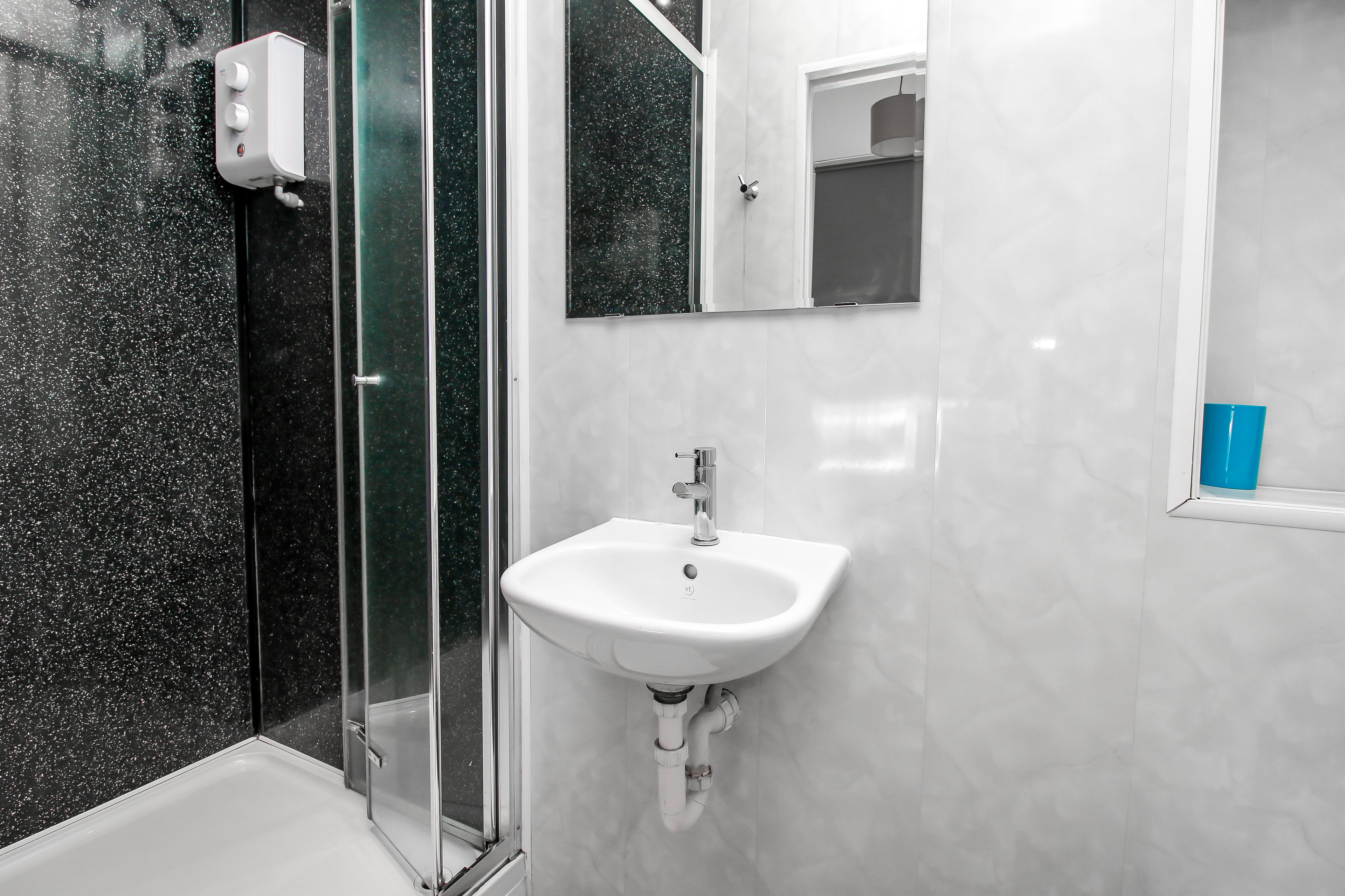 Un baño moderno con cabina de ducha de vidrio, un lavabo blanco y un espejo encima.