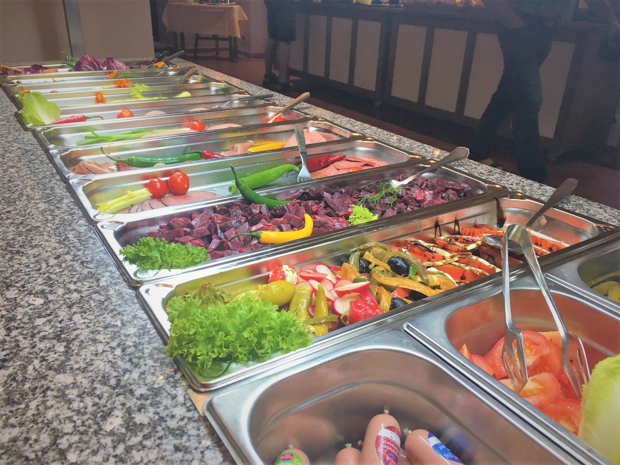 A buffet with various food items including vegetables, meats, and salads.