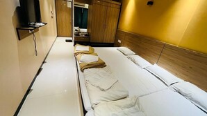 Una habitación de hotel con una cama grande, un televisor montado en la pared y un armario de madera.
