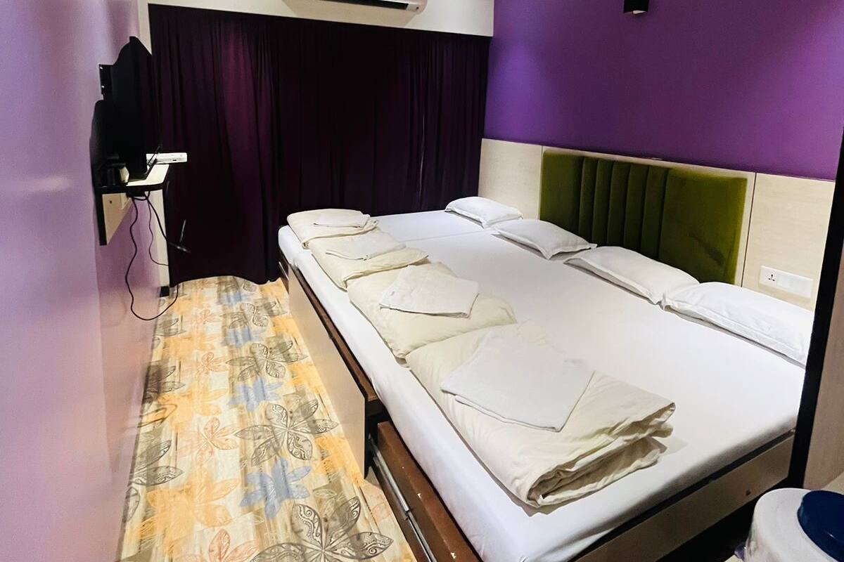 Una habitación de hotel con cama, escritorio, aire acondicionado y baño.