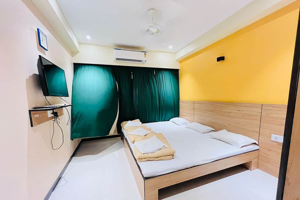 Una habitación de hotel moderna con una cama, un televisor de pantalla plana, un equipo de aire acondicionado y un reloj en la pared.