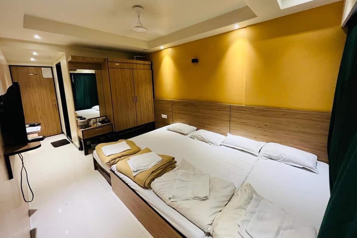 Una habitación de hotel con cama, armario, espejo y televisor.