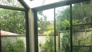 Ein Badezimmer mit großem Fenster, einer Badewanne und Blick auf einen Garten.