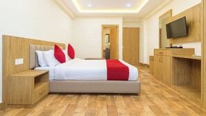 A modern hotel room with a large bed, wooden furniture, a television, and a bathroom visible through an open door. - Golden Dolma (Darjeeling)