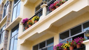 A multi-story building with balconies adorned with potted plants. - Golden Dolma (Darjeeling)