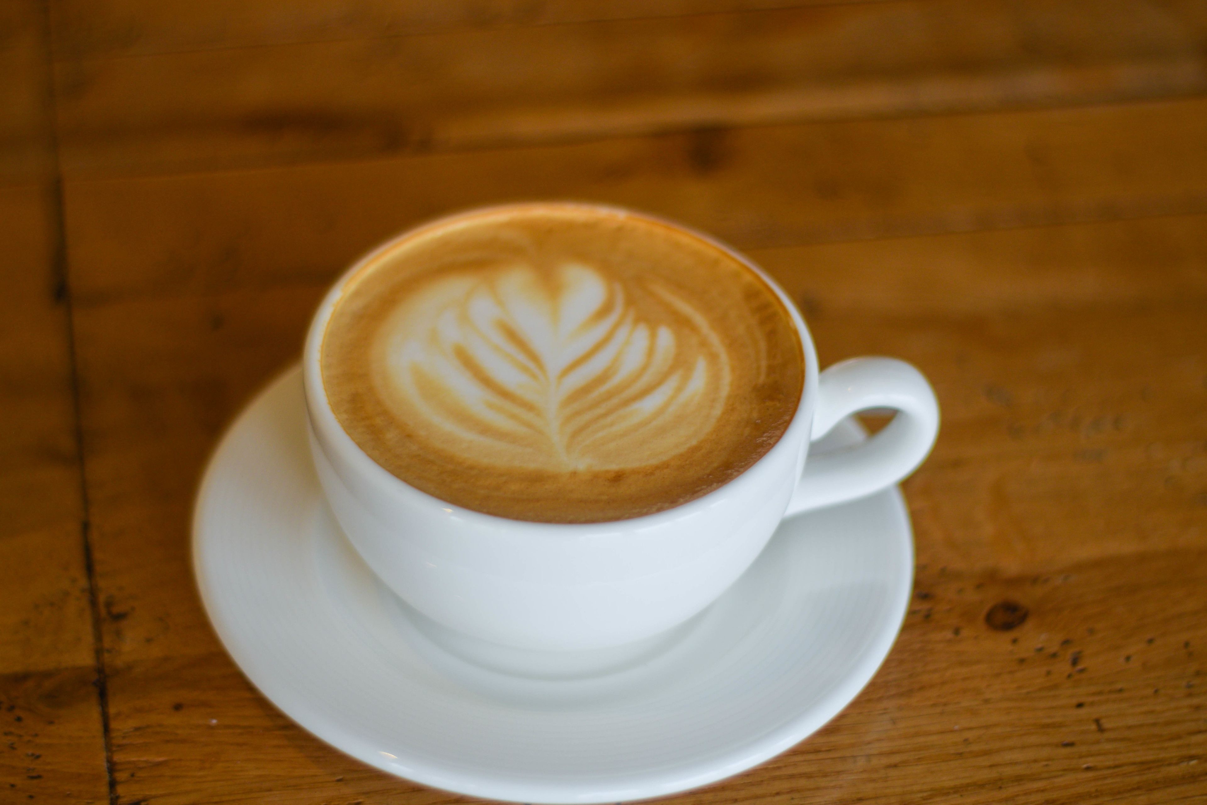Una taza de café con arte latte sobre una mesa de madera.