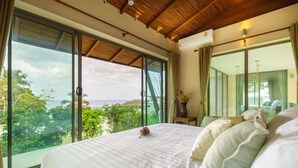 Une chambre dotée d’un grand lit, offrant une vue sur l’extérieur et dont le plafond est orné de poutres en bois.