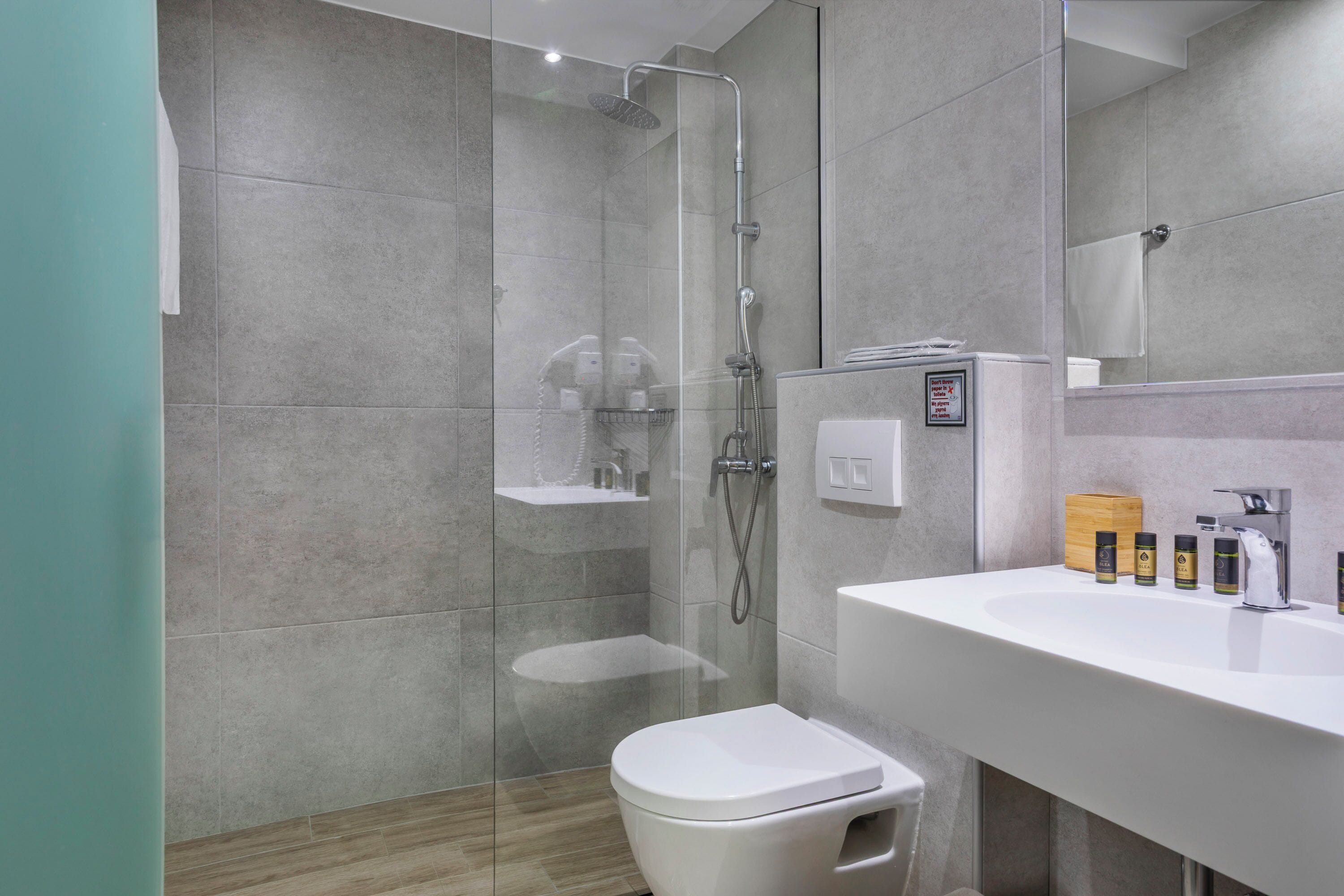 Un baño moderno con ducha de vidrio, lavamanos blanco y un inodoro.