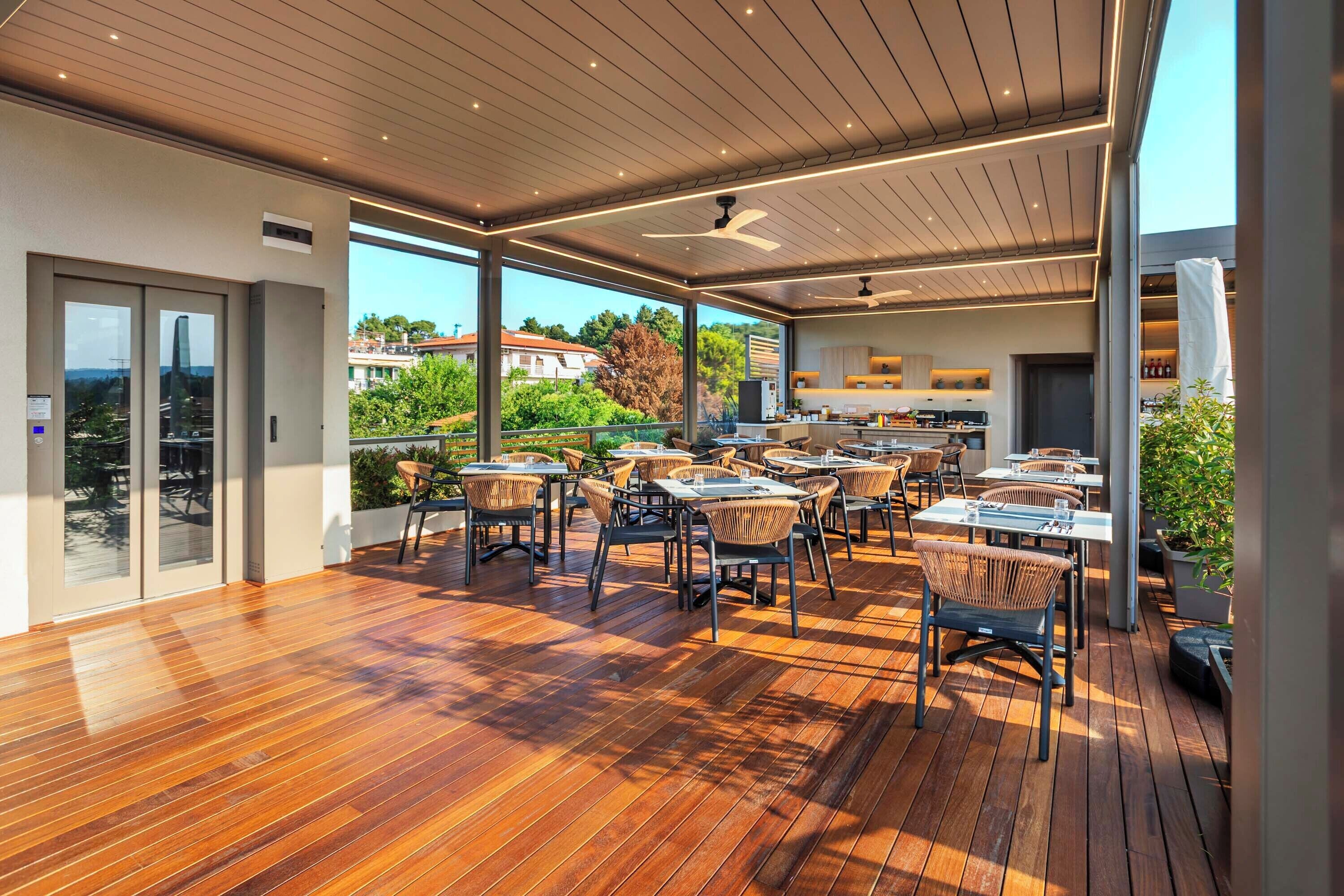 An outdoor dining area with wooden flooring and wicker chairs, overlooking a scenic landscape.