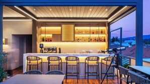 An outdoor bar area with a wooden ceiling, a bar counter, and several chairs. - Hotel Vozina (Polygyros)