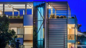 A modern building with large glass windows and a balcony with plants. - Hotel Vozina (Polygyros)