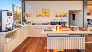 A modern kitchen with wooden cabinets, a built-in coffee machine, and a variety of food items on the counter. - Hotel Vozina (Polygyros)