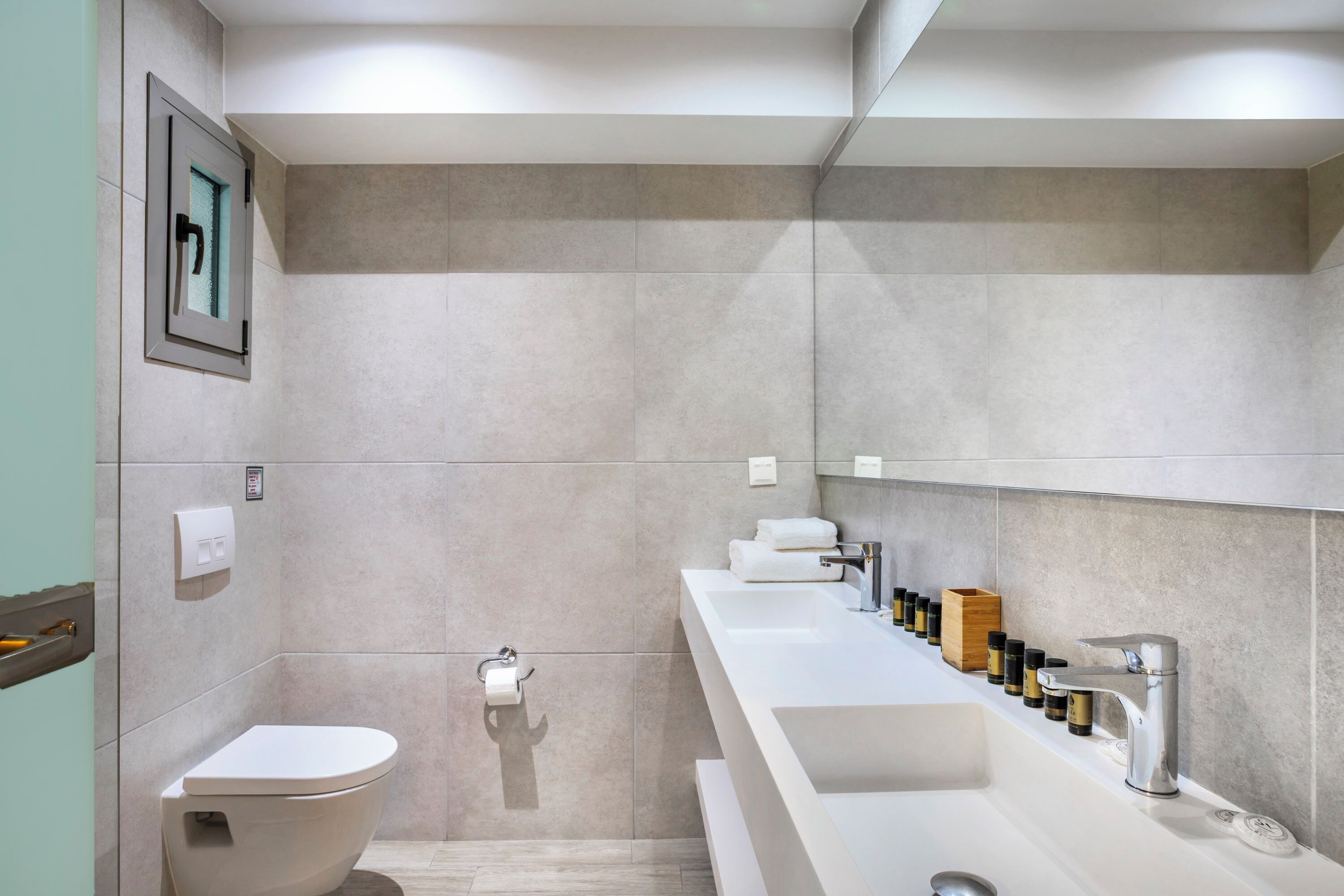 Ein modernes Badezimmer mit Toilette, Waschbecken und Spiegel.