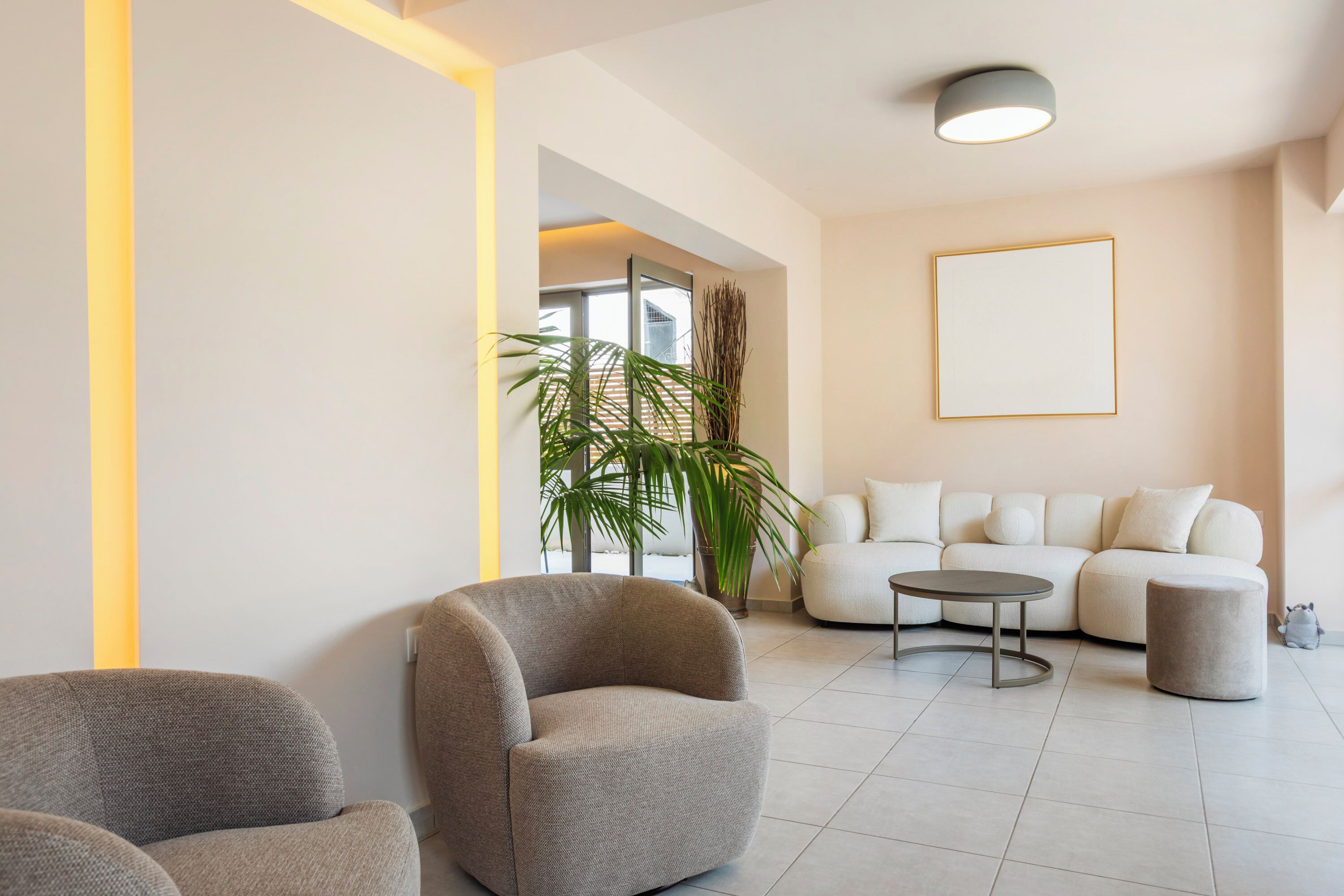 A modern living room with a sofa, two armchairs, a coffee table, and a potted plant.