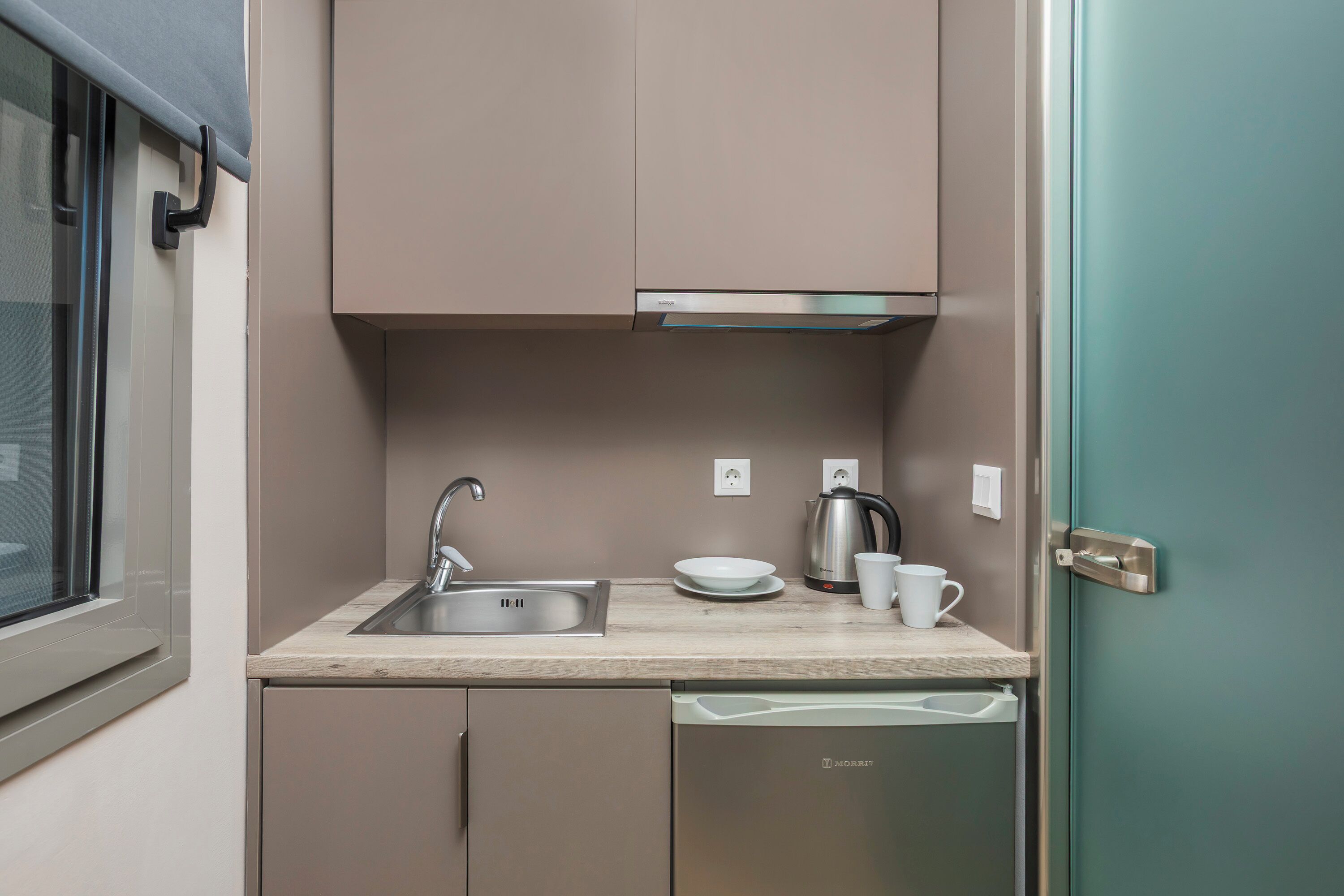Una kitchenette compacta con un lavabo, una cafetera y un lavavajillas.