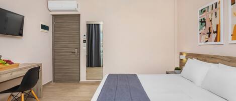 Habitación de hotel con cama, escritorio con silla, televisor y obras de arte en la pared.