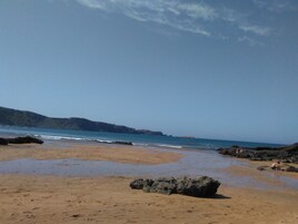 A beach with rocky outcrops and calm waters.