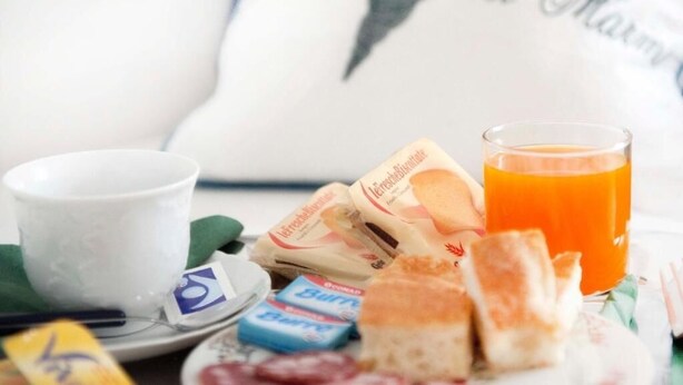 Desayuno con una taza, jugo, galletas y un plato con un sobre de azúcar.