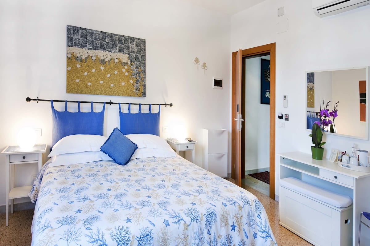 A bedroom with a bed, a nightstand, a dresser, a mirror, and a door.