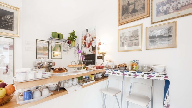 A breakfast bar with various food items, a coffee machine, and framed pictures on the wall. - A Due Passi (Forte dei Marmi)