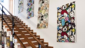 A staircase with wooden steps and a metal handrail, leading to a landing with a wall decorated with colorful, cartoon-style artwork. - A Due Passi (Forte dei Marmi)