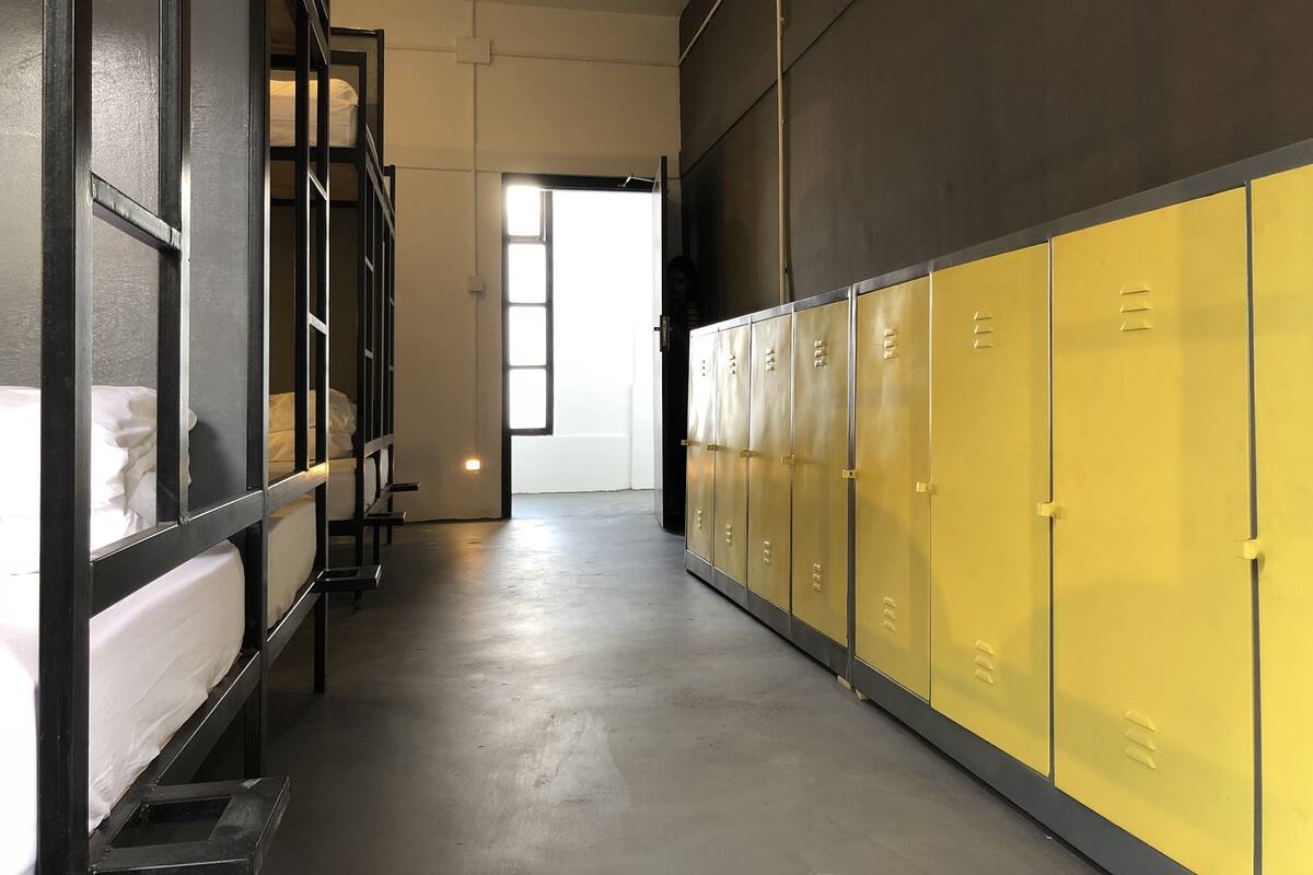 A hallway with bunk beds on the left and yellow lockers on the right.