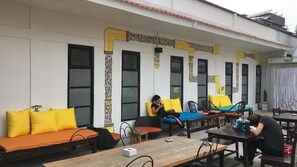 An outdoor seating area with sofas and tables, a building with decorative elements, and a sign that reads "POINTERS". - Yakety Yak Hostel (Kathmandu)