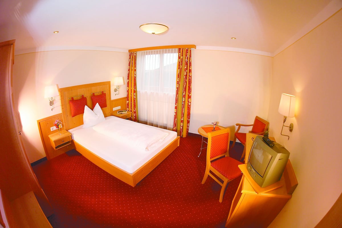 Une chambre d’hôtel avec un grand lit, une télévision, une chaise et une petite table.